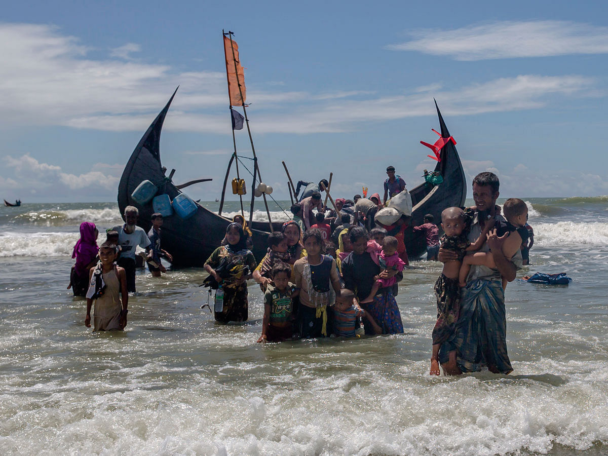 In this 14 September 2017 file photo, a Rohingya man carries two children to shore in Shah Porir Dwip, Bangladesh, after they arrived on a boat from Myanmar. The UN refugee agency says nearly 69 million people who have fled war, violence and persecution were forcibly displaced last year, a new record for the fifth straight year. The UN High Commissioner for Refugees said Tuesday, 19 June 2018 that continued crises in places like South Sudan and Congo, as well as the exodus of Muslim Rohingya from Myanmar starting last year, raised the overall figure of forced displacements in 2017 to 68.5 million. Photo: AP