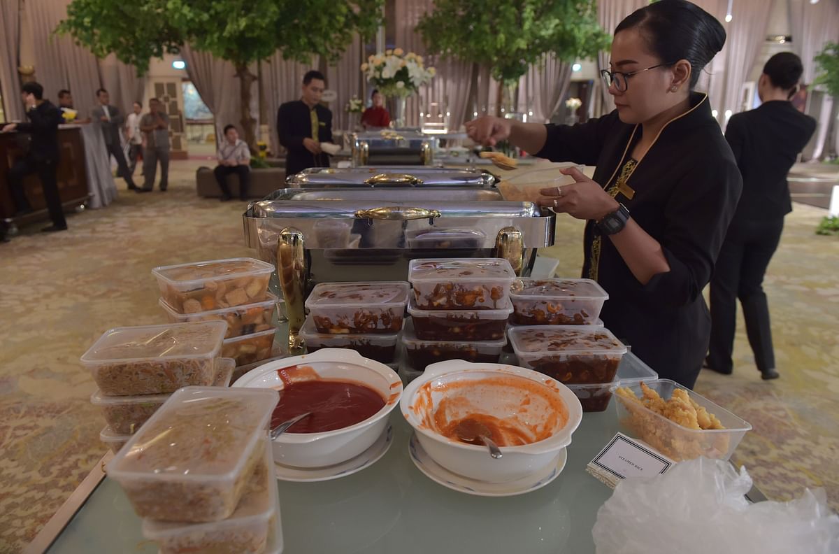 This picture taken on 19 March 2018 shows a waitress packing uneaten food for distribution through the programme `A Blessing to Share`, after a wedding at a hotel in Jakarta. In the slums of Jakarta, Indonesia`s poor are getting a taste of how the other half live thanks to a new programme that aims to take a bite out of its mammoth food-waste problem. Photo: AFP