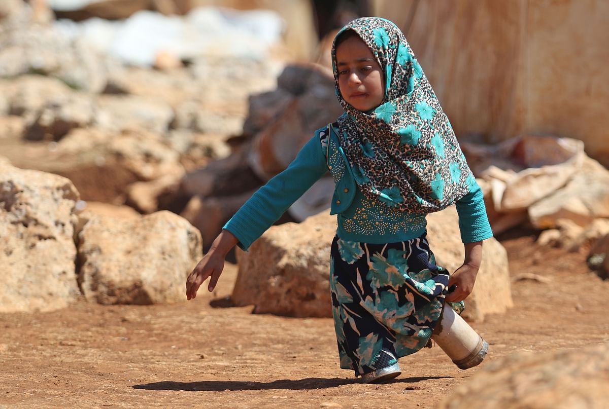 Eight year-old Maya Mohammad Ali Merhi walks using prosthetic legs made by her father from tin cans in a camp for displaced people, in the northern Syrian province of Idlib on 20 June 2018. Maya and her father were both born without lower limbs. Unable to afford real prosthetic limbs, her father made her a pair out of tin cans filled with cotton and scrap pieces of cloth. Maya`s family had to leave their home in the Aleppo province to flee battles. Photo: AFP