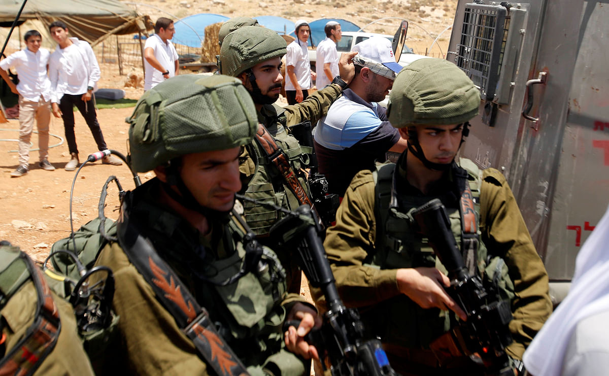Israeli soldiers detain a Palestinian during a protest against a new Jewish settlement outpost near Hebron in the occupied West Bank, on 23 June 2018. Photo: Reuters