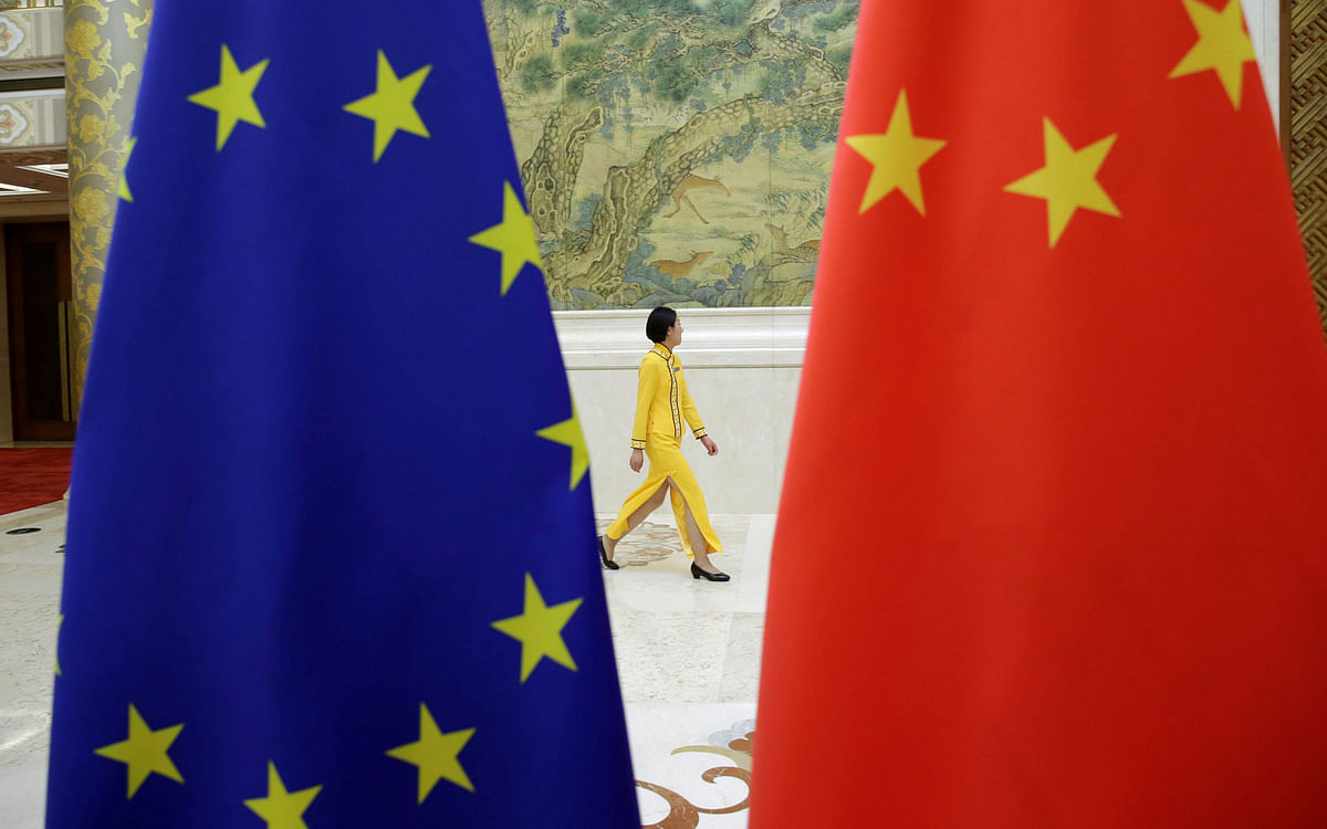 An attendant walks past EU and China flags ahead of the EU-China High-level Economic Dialogue at Diaoyutai State Guesthouse in Beijing, China on 25 June. Photo: Reuters