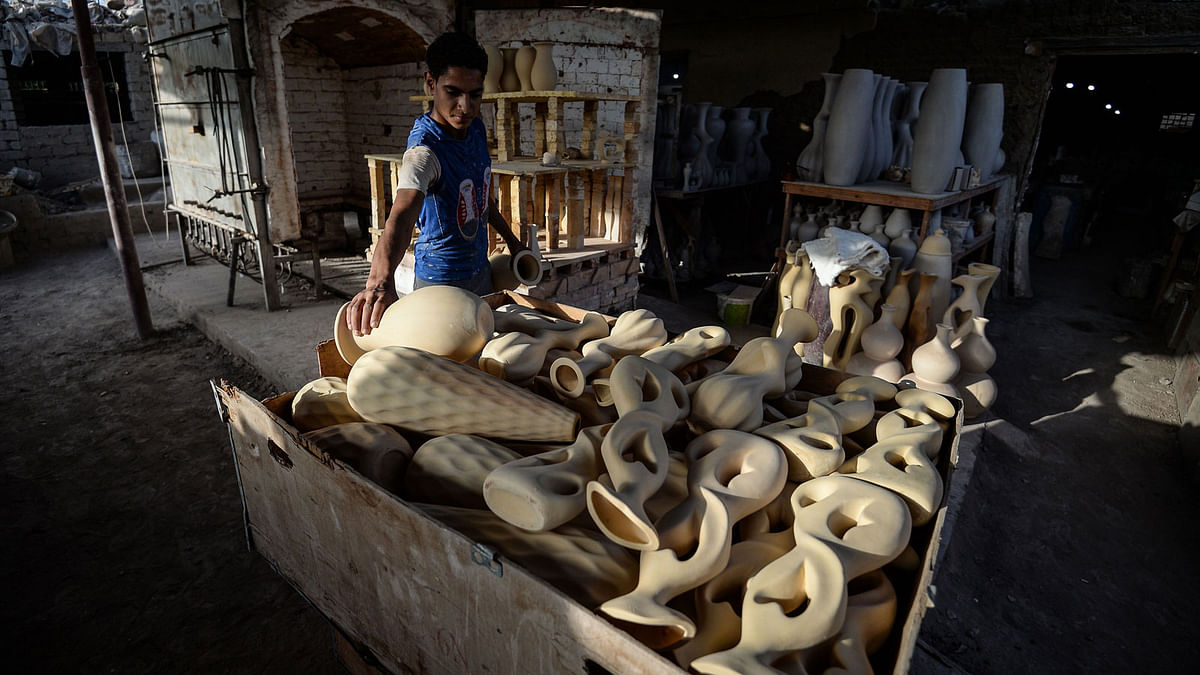 One of Mostafa el-Agoury`s employees prepares pieces to be dried at his pottery workshop in the village of Shamma in Egypt`s Nile Delta Menoufiya province on 21 June 2018. Photo: AFP
