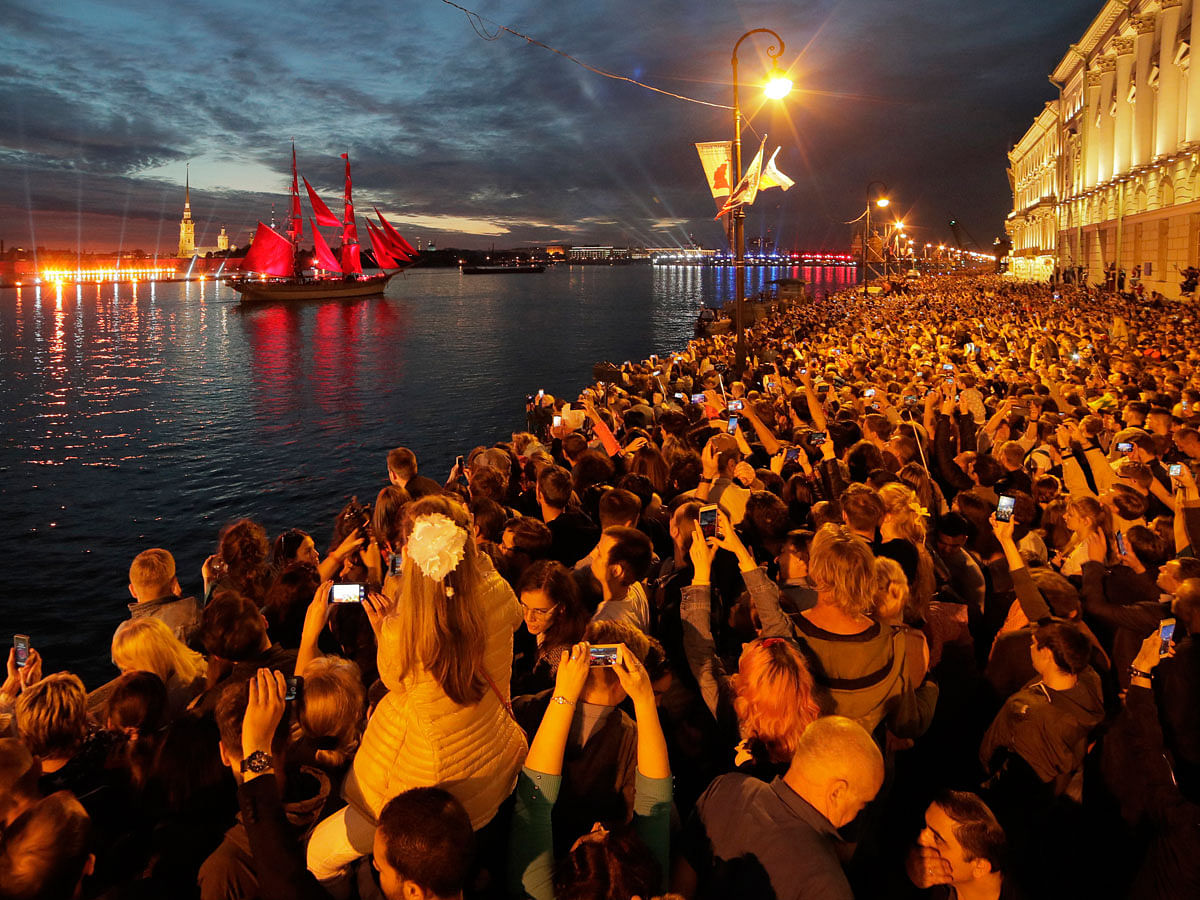 People watch a brig with scarlet sails on the Neva River during the Scarlet Sails festivities marking school graduation in St.Petersburg, Russia on 24 June. Photo: AP