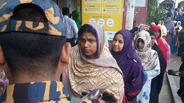 A member of Border Guard Bangladesh (BGB) keeps watch as women voters wait to cast their votes in the Gazipur City Corporation at Chandana High School and College centre on 26 June. Photo: Sajid Hossain