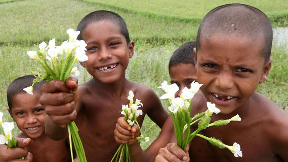 Smiling children with wildflowers in Maliandanga village of Gabtoli upazila, Bagura on 25 June. Photo: Soel Rana