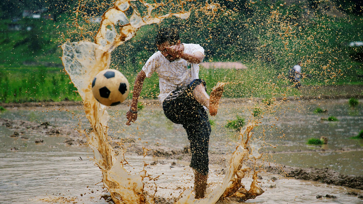 A man kicks a football as he takes part in an event celebrating National Paddy Day, also called Asar Pandra, that marks the commencement of rice crop planting in paddy fields লas monsoon season arrives, in Lalitpur, Nepal on 29 June. Reuters
