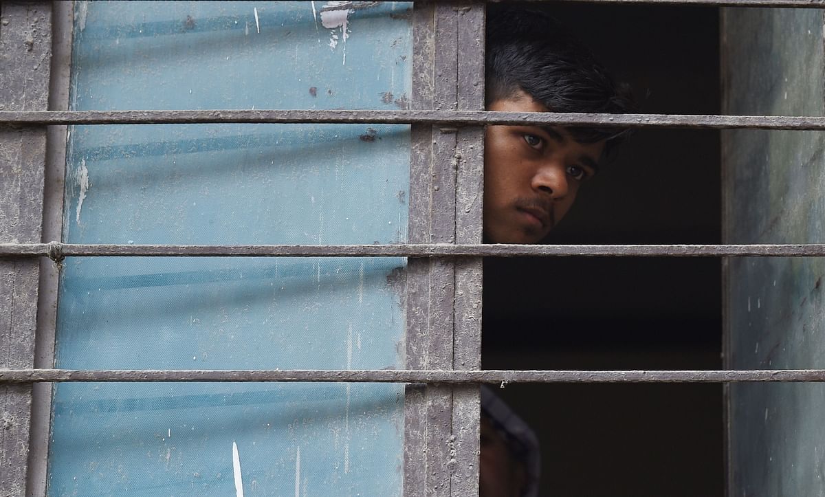 A neighbour looks out from a window near the building where 11 family members were found dead inside their home in the neighbourhood of Burari in New Delhi on 1 July 2018. Police have cordoned off the home in Burari in the north of the capital where the bodies of seven women and four men were discovered July 1. `10 of the 11 family members were found hanging when we reached the house. The last, a 75-year-old female, was dead on the floor,` a Delhi police official told AFP. Photo: AFP
