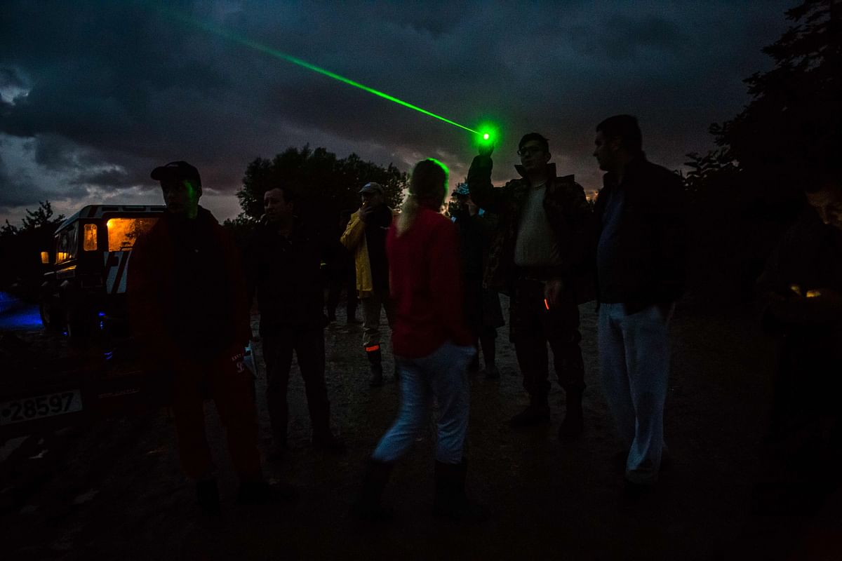 Inhabitants from Bacel village are using a laser pointer to light the way back for the Romanian General Emergency Inspectorate boats which are attempting to carry stranded people to safety on 30 June 2018, in Covasna county, Romania. Photo: AFP