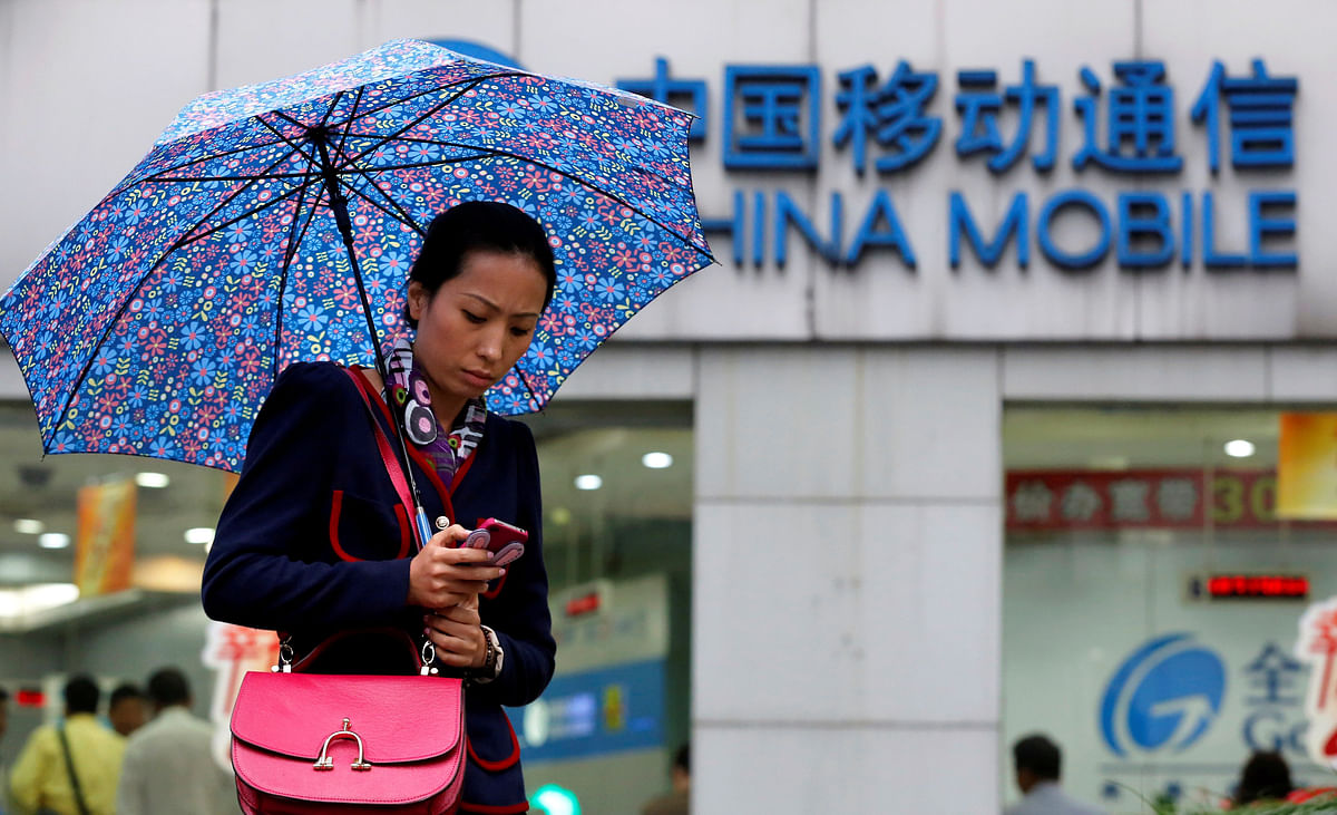 A woman uses her mobile phone in front of a China Mobile office in downtown Shanghai on 22 October 2012. Photo: Reuters