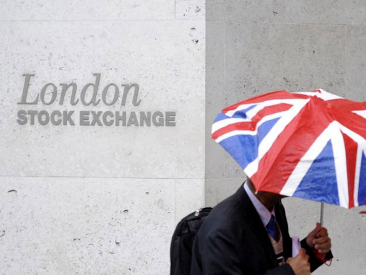 A worker shelters from the rain as he passes the London Stock Exchange in the City of London at lunchtime on 1 October 2008. -- Reuters
