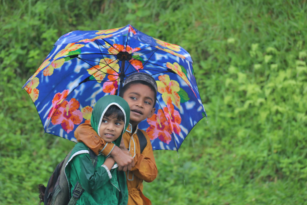 A boy and a girl try to save themselves from incessant rain with an umbrella in Guimara upazila of Khagrachhari on 3 July. Photo: Nerob Chowdhury