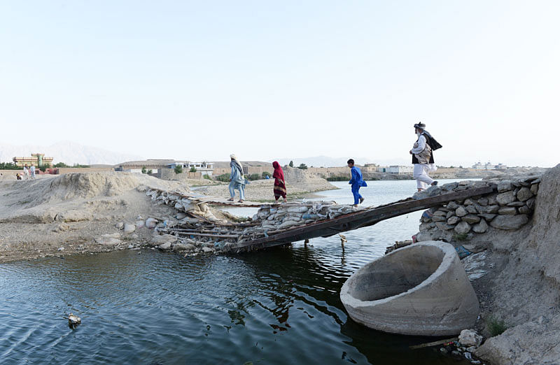 Afghan residents walk across a bridge on the outskirts of Kabul on 29 June 2018. Photo: AFP
