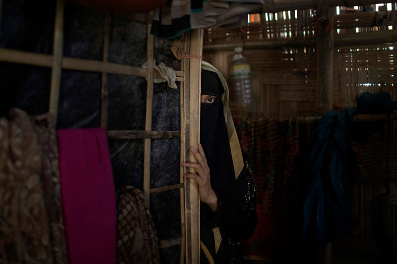 In this Tuesday, 26 June 2018, photo, ‘A’, a 13-year old Rohingya Muslim girl who agreed to be identified by her first initial, peers from behind a partition in her family`s shelter in Jamtoli refugee camp in Bangladesh. Photo: AP