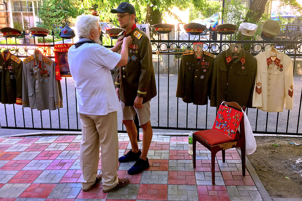 A local assists a tourist with putting on a Russian military costume outside the entrance to Stalin`s Bunker in Samara in Russia, 1 July 2018. Photo: Reuters