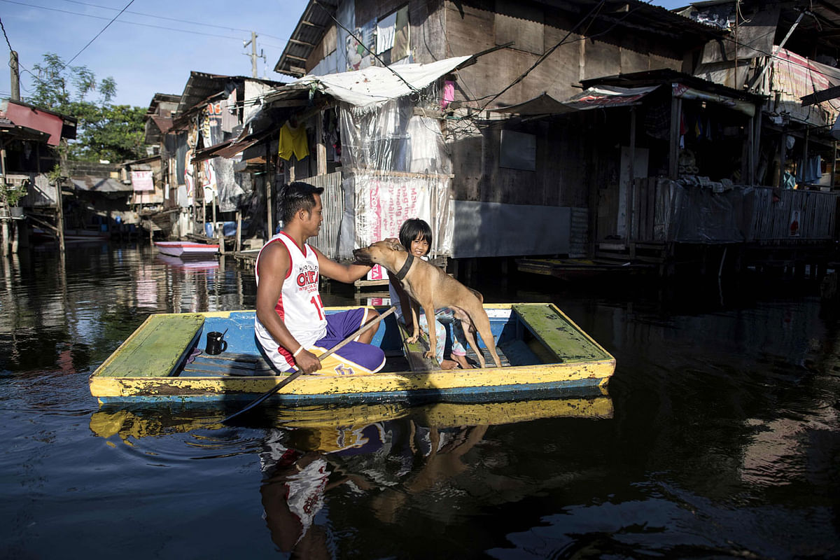 Residents ride on a makeshift boat to cross stagnant floodwaters in the Artex Compound in Manila on 6 July. Health officials have said that the surge in leptospirosis cases can be attributed to seasonal flooding due to continuous rains in recent weeks. Photo: AFP