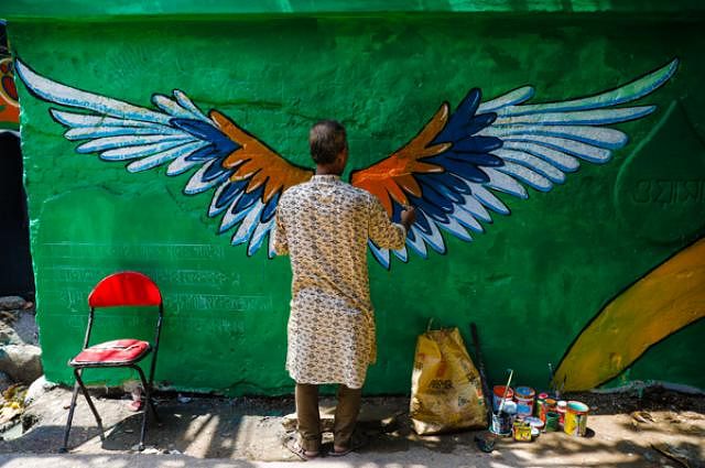 A participant paints wings on the wall.