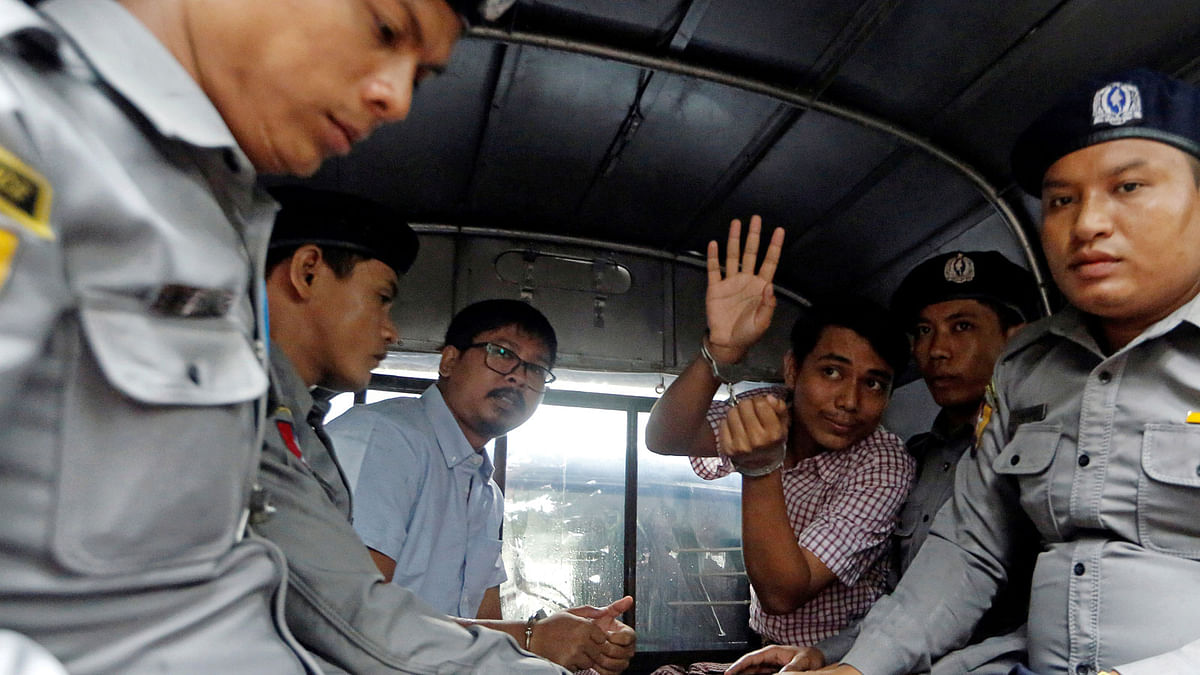 Detained Reuters journalist Wa Lone and Kyaw Soe Oo sit beside police officers as they leave Insein court in Yangon. Photo: Reuters