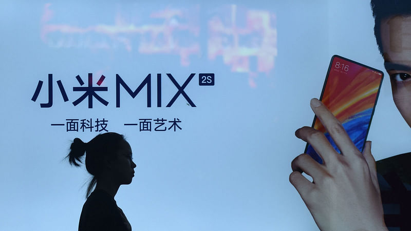 A woman walks past a light box advertisement of Xiaomi in Beijing on 9 July. Photo: AFP