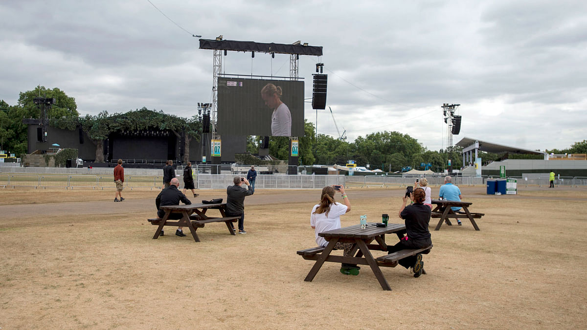 People sit watching wimbledon on the big screen as final preparations are made at British Summer Time (BST) event in Hyde Park, London, where 30,000 football fans are expected to watch England`s World Cup semi-final against Croatia, Tuesday 10 July 2018. England will play Croatia in the World Cup soccer semi-final on Wednesday. Photo : AP