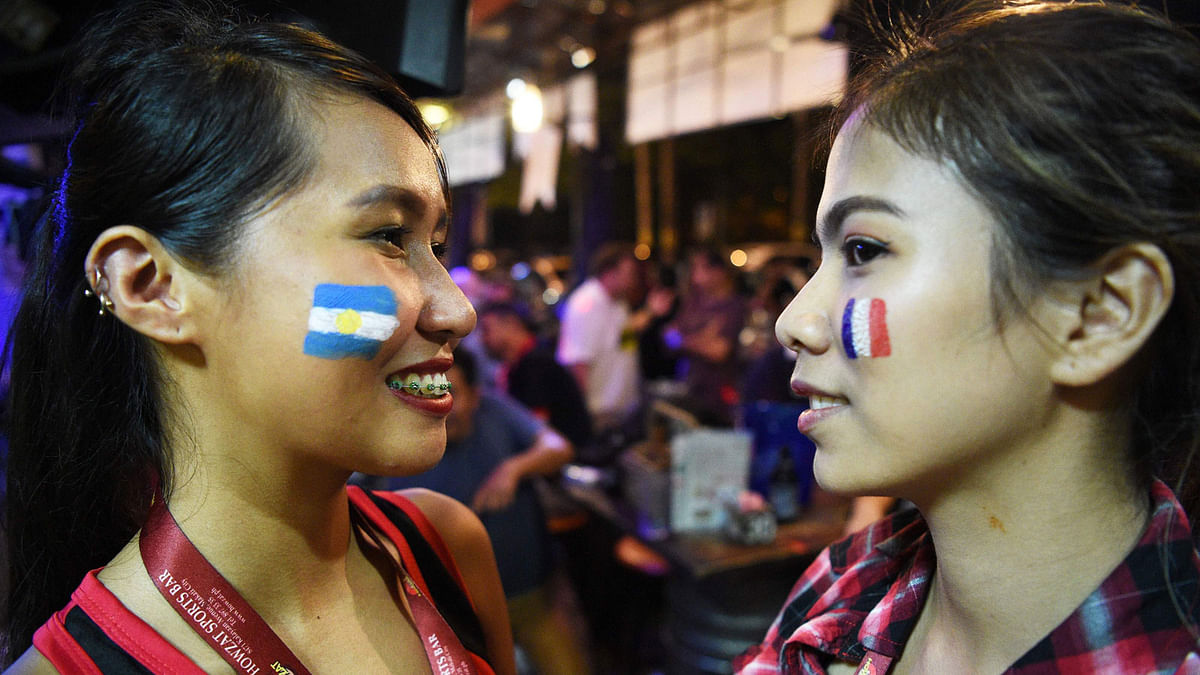 This photo taken on 30 June 2018 shows bar staff displaying their faces painted with the flags of France (R) and Argentina (L) as fans watch the 2018 Russia World Cup match between France and Argentina at a bar in Manila. Shirts are selling briskly, crowds pack sports bars to watch matches and football is front-page news. Whisper it quietly, but basketball-crazy Philippines has finally been afflicted by World Cup fever. Photo: AFP