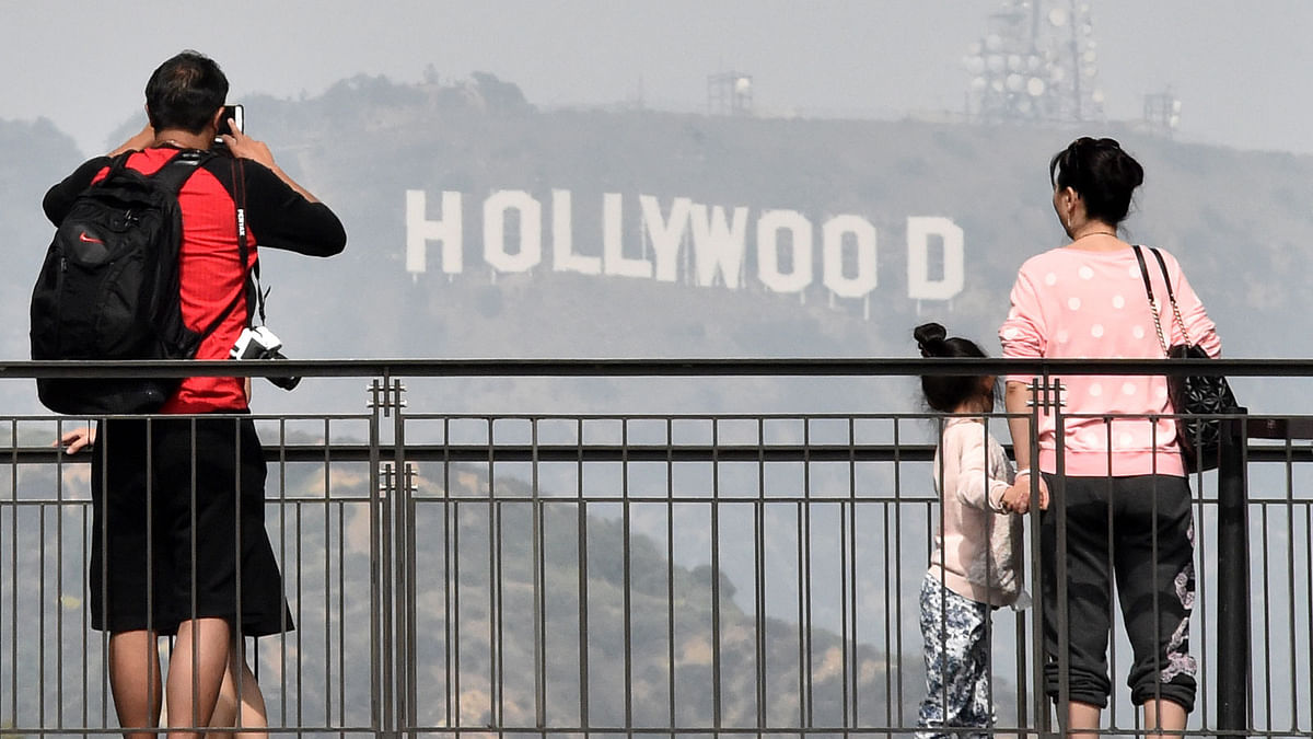 In this file photo taken on February 20, 2015 tourists watch and photograph the Hollywood sign from a terrace at the shopping mall outside Dolby Theatre. Photo: AFP