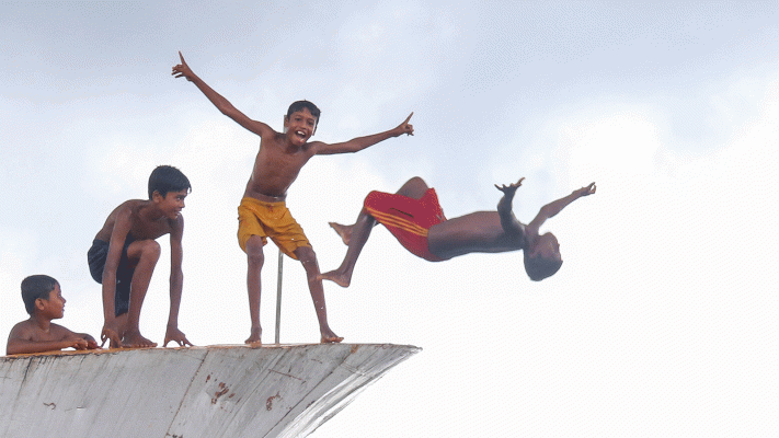 Children jump into the water from a launch at Khulna Rupsha Kheyaghat on 11 July 2018. Photo: Saddam Hossain