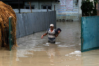 A Nepali man wades through flood water after the Hanumante River overflowed following monsoon rain in the Thimi area of Bhaktapur on the outskirts of Kathmandu on 12 July 2018. Photo: AFP