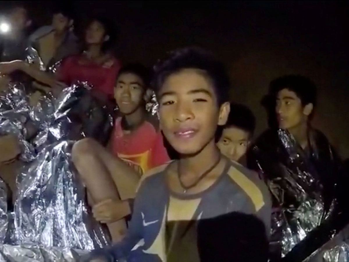 Boys from the under-16 soccer team trapped inside Tham Luang cave covered in hypothermia blankets react to the camera in Chiang Rai, Thailand, in this still image taken from a 3 July, 2018 video by Thai Navy Seal. Photo: Reuters