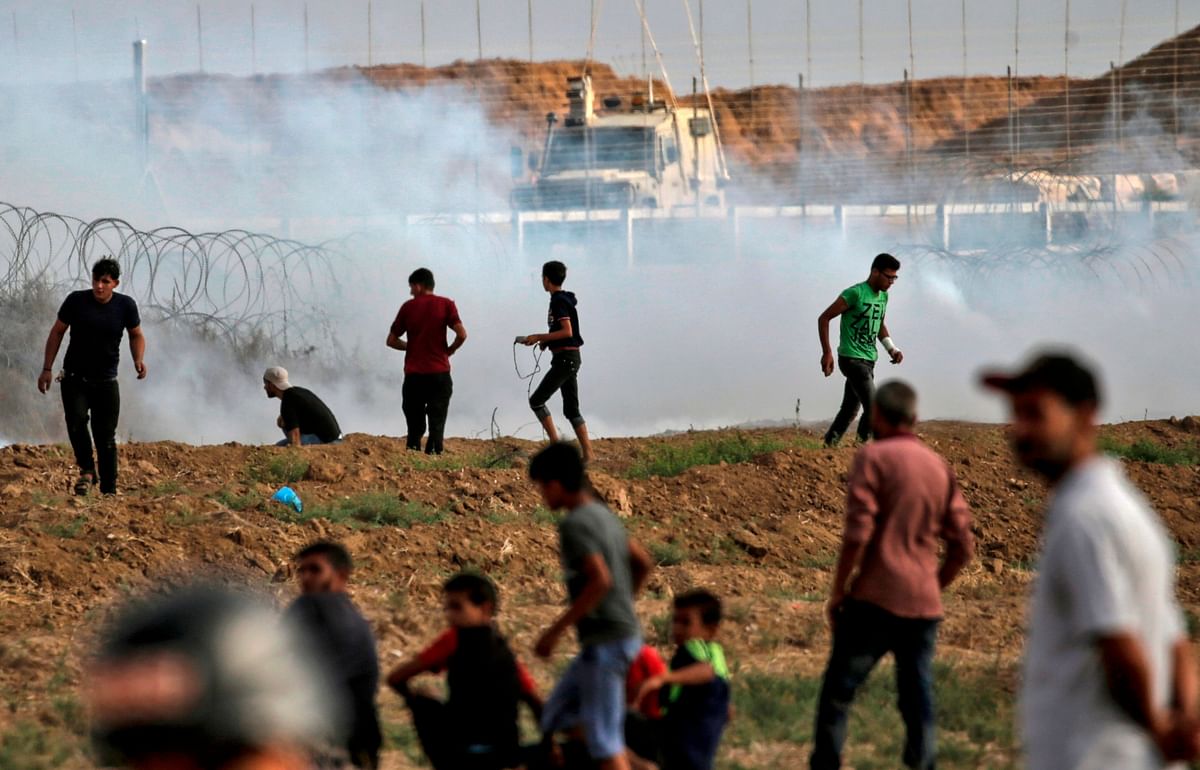 Palestinian protesters are seen standing before tear gas fumes during clashes following a demonstration by the border with Israel east of Gaza city on 13 July. Photo: AFP