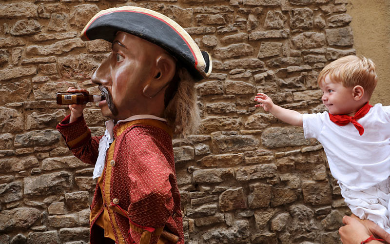 A boy tries to get the attention of a `Kiliki`, which drinks a beer, during San Fermin festival`s `Comparsa de gigantes y cabezudos` (Parade of the Giants and Big Heads) in Pamplona, northern Spain on 13 July. Photo: Reuters