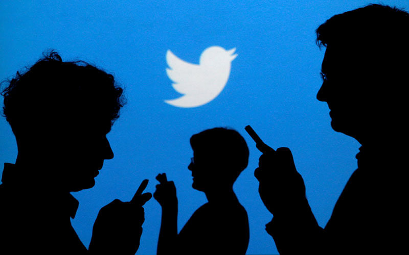 People holding mobile phones are silhouetted against a backdrop projected with the Twitter logo in this illustration picture taken on 27 September 2013. Photo: Reuters