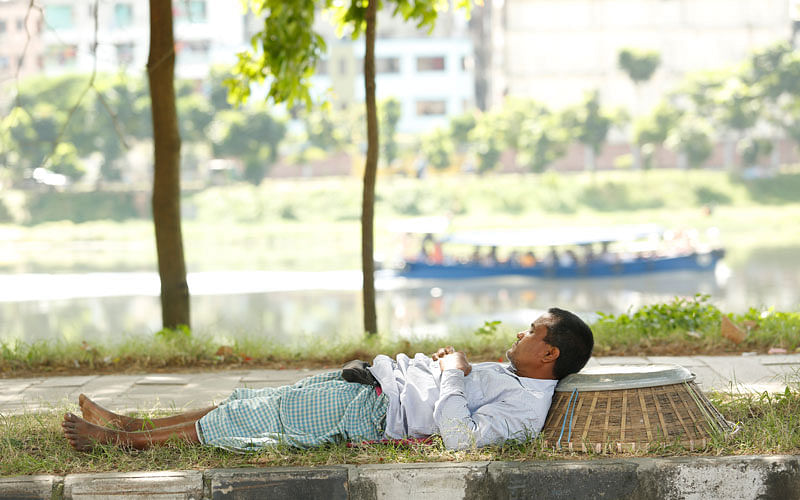 A man rests beneath a tree after weary work day at Hatirjheel in Dhaka. Photo: Sumon Yusuf