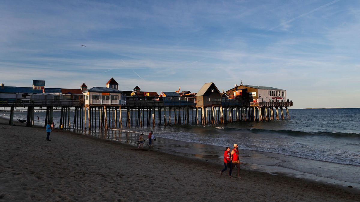 In this 26 June 2018 photo, vacationing tourists stroll along the edge of the Atlantic Ocean near The Pier in Old Orchard, Beach, Maine. Canadians may be angry about president Donald Trump`s insults and tariffs, but it doesn`t seem to be taking a toll on tourism. In Old Orchard Beach, popular with Canadians from French-speaking Quebec, innkeepers report that tourism remains strong despite harsh words. Photo : AP