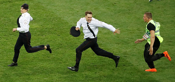 Pitch invaders are chased by a steward during the match. Photo: Reuters