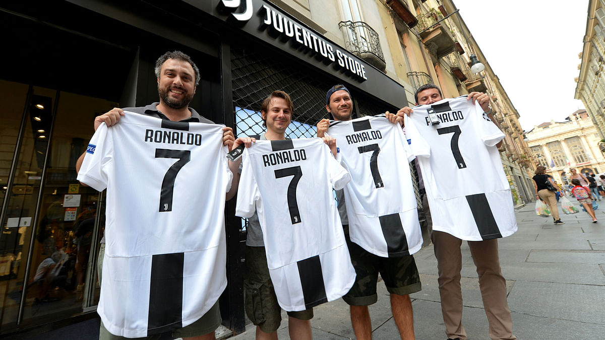 Juventus supporters hold, after buying, the original Juventus` jersey printed with the name and number of Cristiano Ronaldo after his transfer to Juventus in Turin. Reuters