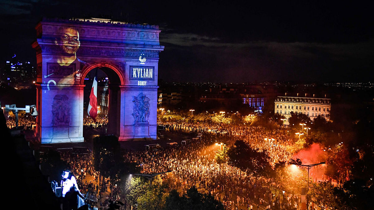 This picture taken from the terrace of the Publicis drugstore on 15 July shows a portrait of French forward Kylian Mbappe projected on Paris` landmark Arc de Triomphe as people gather to celebrate France`s victory in the Russia 2018 World Cup final football match between France and Croatia, on the Champs-Elysees avenue in Paris. Photo: AFP