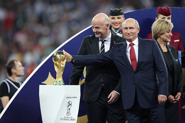 President of Russia Vladimir Putin touches the trophy as FIFA president Gianni Infantino looks on before the trophy presentation. Photo: Reuters