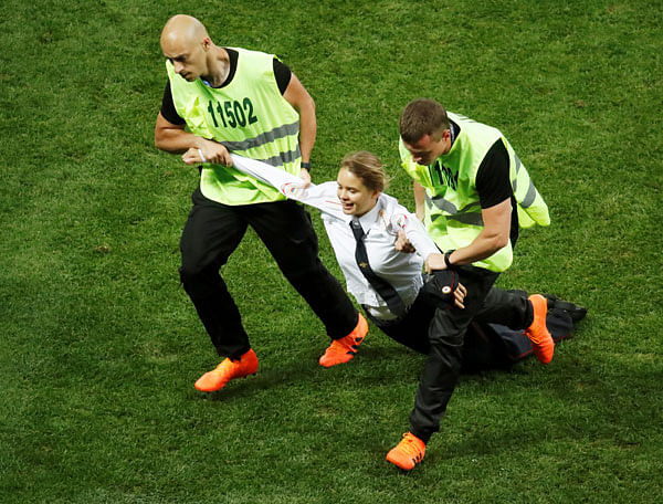 Stewards apprehend a pitch invader during the match. Photo: Reuters