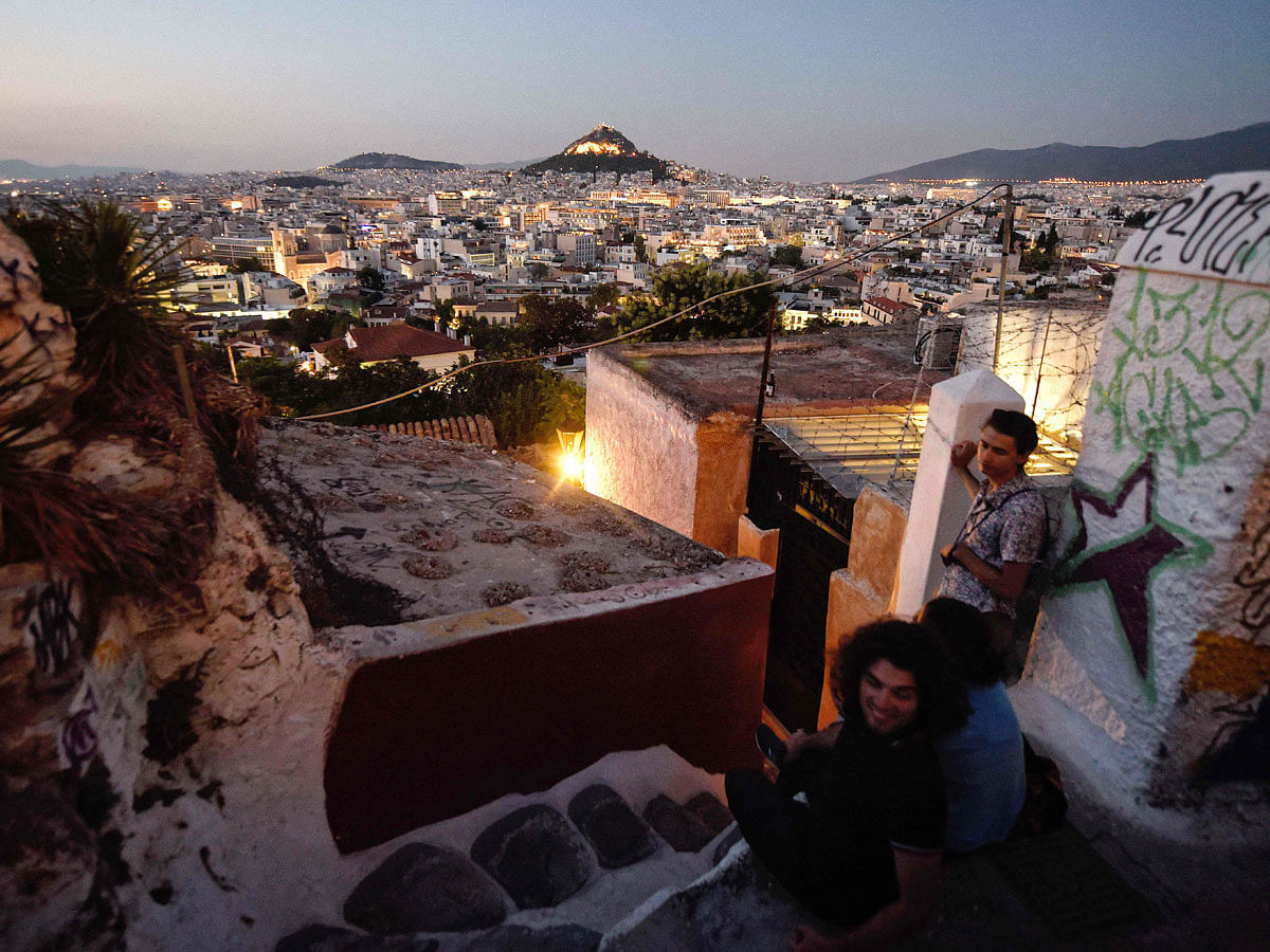 Tourists take in the veiw from the tiny Anafiotika district of Athens, under the Acropolis archaeological site on 11 July, 2018. Photo: AFP