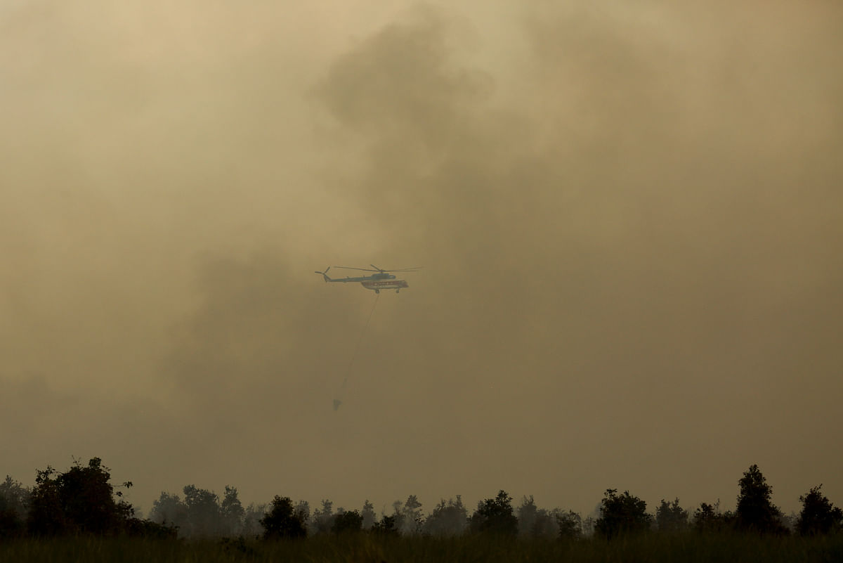 A helicopter carrying a water bucket is seen after dropping water on a forest fire in Ogan Komering Ilir, South Sumatra Province, Indonesia 17 July 2018. Photo: Reuters