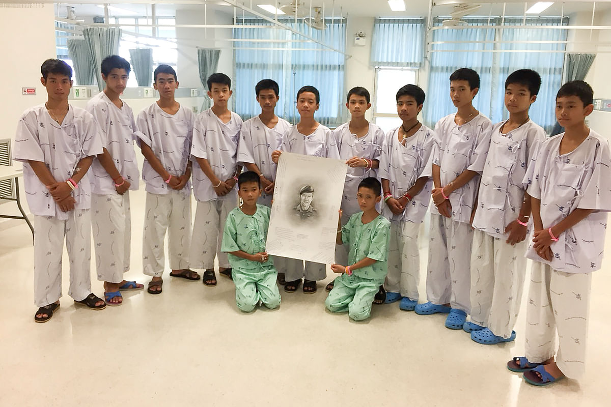 The 12-member `Wild Boars` soccer team and their coach rescued from a flooded cave pose with a drawing picture of Samarn Kunan, a former Thai navy diver who died working to rescue them at the Chiang Rai Prachanukroh Hospital, in Chiang Rai, Thailand on 14 July 2018. Photo: Reuters