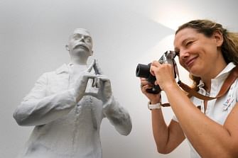 In this file photo taken on 12 July 2017 a staff of the Paris 2024 Olympic bid team takes a picture of a reproduction of a statue of International Olympic Committee (IOC) founder Pierre de Coubertin gesturing to make the form of the Eiffel tower, within the presentation of Paris 2024 bid in Lausanne. AFP