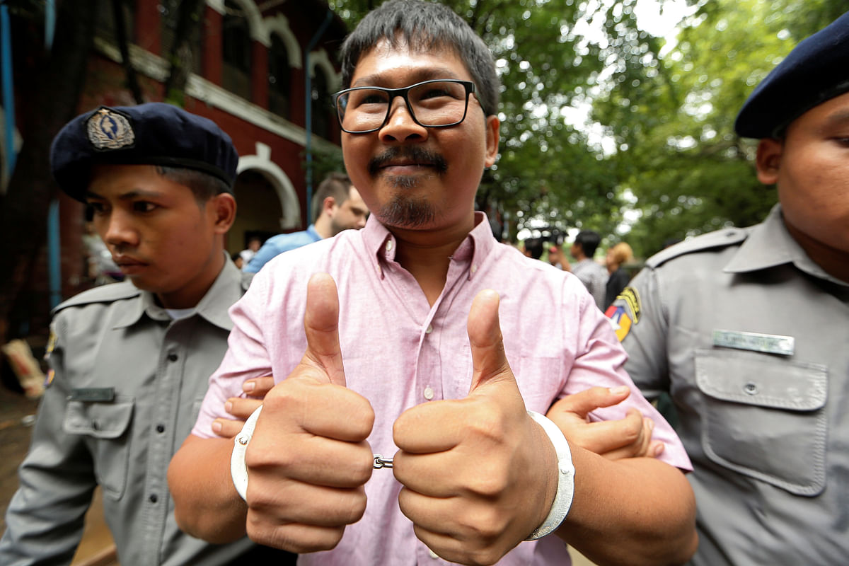 Detained Reuters journalist Kyaw Soe Oo is escorted by police while leaving Insein court in Yangon. Photo: Reuters