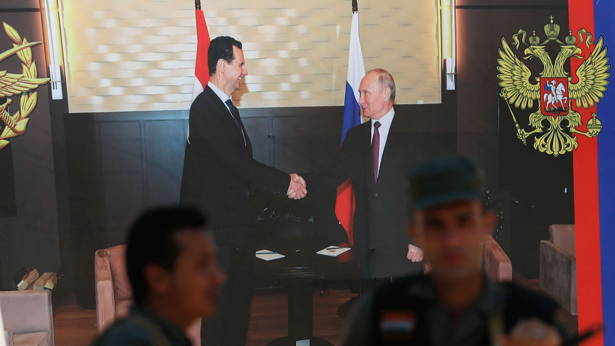 Syrian policemen stand guard in front of poster of Syrian president Bashar Assad and Russian president Vladimir Putin, right, at a check point on the entrance of the central Syrian town of Rastan, Homs province, Syria, Tuesday, 17 July 2018.