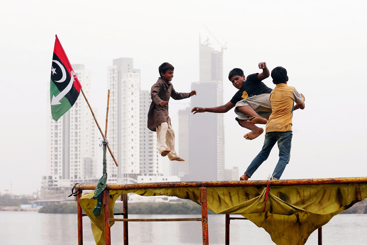 Children play on a trampoline, near electoral flag of a political party, with the under-construction buildings in the background, in a low-income neighbourhood in Karachi, Pakistan on 18 July 2018. Photo: Reuters