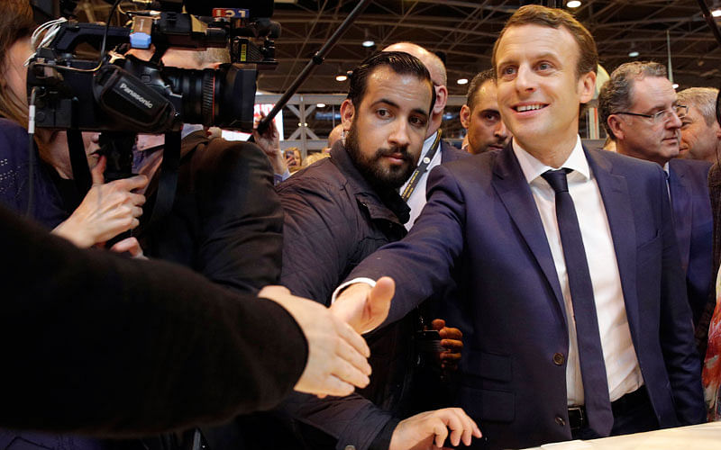 FILE - In this 1 March 2017 file picture centrist presidential candidate Emmanuel Macron, center, flanked by his bodyguard, Alexandre Benalla, left, visits the Agriculture Fair in Paris, Wednesday, 1 March 2017. Benalla an aide to president Emmanuel Macron, charged with security, has been seen in a video wearing a police helmet and beating up a student protester in May, reigning criticism on Macron notably due to the light punishment _ a two-week suspension. Photo : AP
