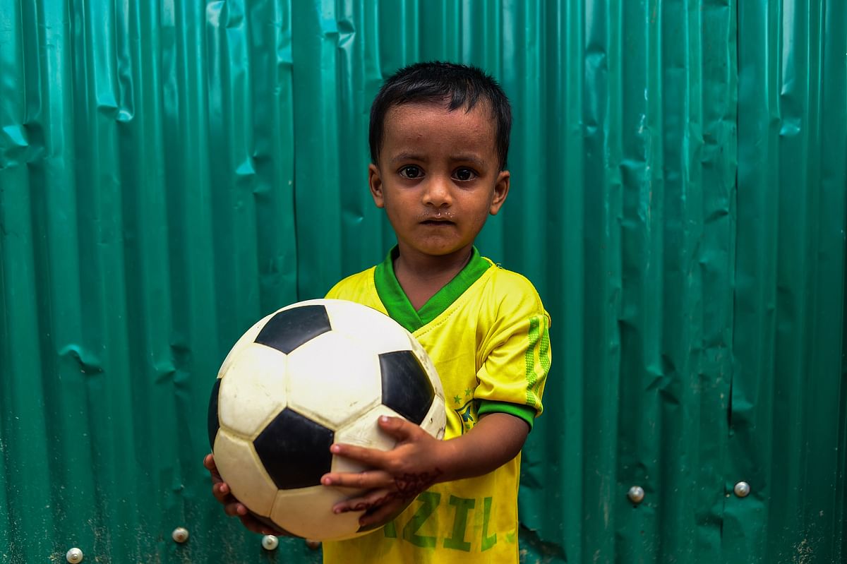 In this picture taken on July 19, 2018, Rohingya refugee child Mohammad Raihan poses for a photo wearing a Brazil jersey while holding a football at the Kutupalong refugee camp in Ukhia on 19 July 2018. AFP