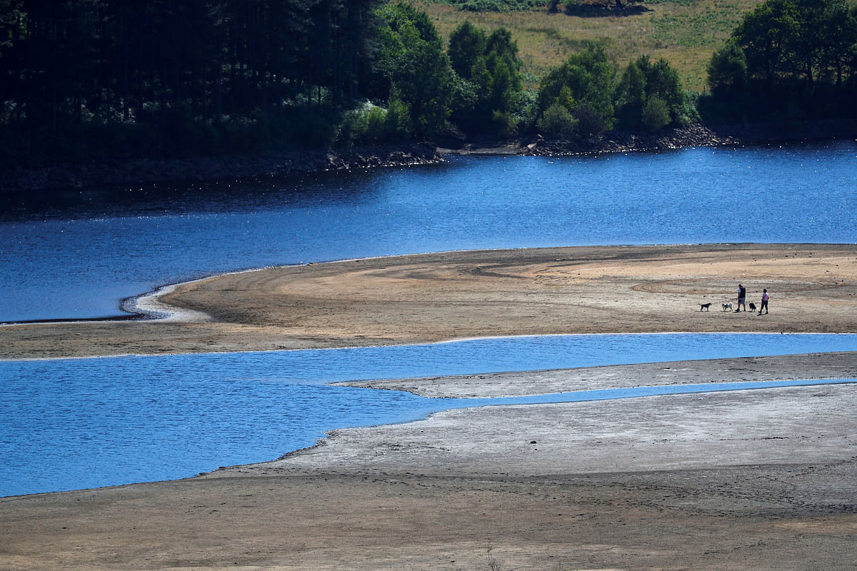 Two people take a walk near the water`s edge, where the water level has dropped significantly during the UK heatwave, of Torside Reservoir in Longdendale, Derbyshire, Britain, on 3 July 2018. Photo: Reuters