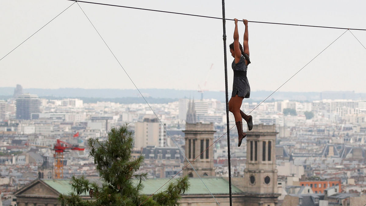 Tightrope walker Tatian-Mosio Bongonga hangs from a tightrope as she pauses while scaling the Monmartre hill towards the Sacre Coeur Basilica in Paris, France on 20 July. Photo: Reuters