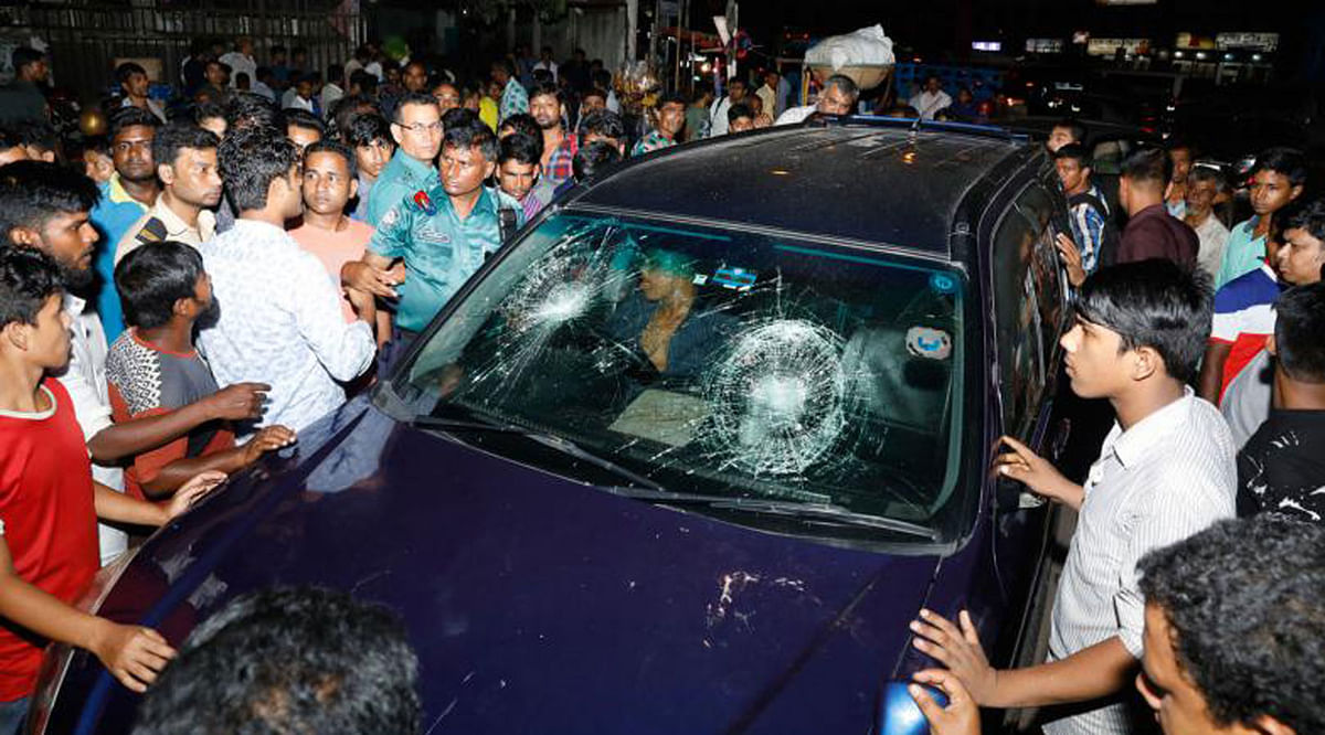 An angry mob beat up the driver in the car in this 22 July picture. The reckless driver drove the vehicle over a woman at Karwan Bazar, Dhaka.